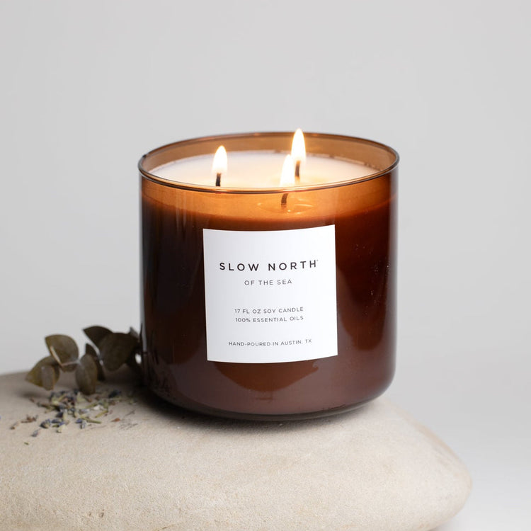 Of The Sea three-wick candle lit in an amber glass jar