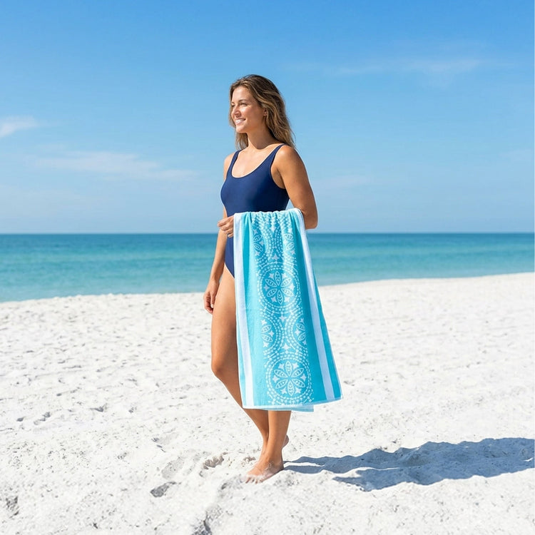 Woman holding a turquoise Drytek towel on a beach